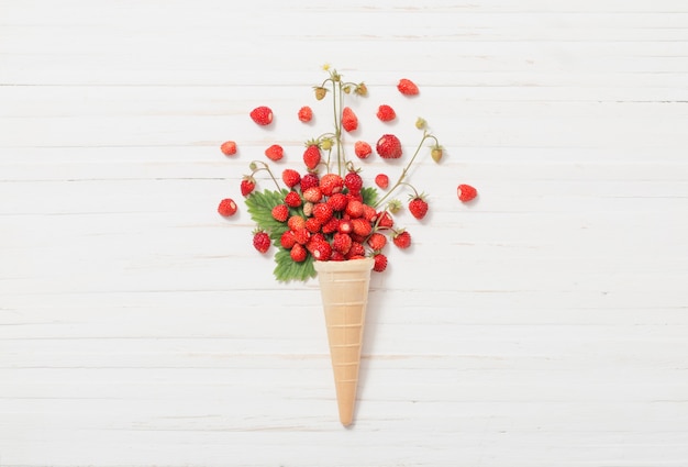 Waffle cone with strawberries on wooden wall