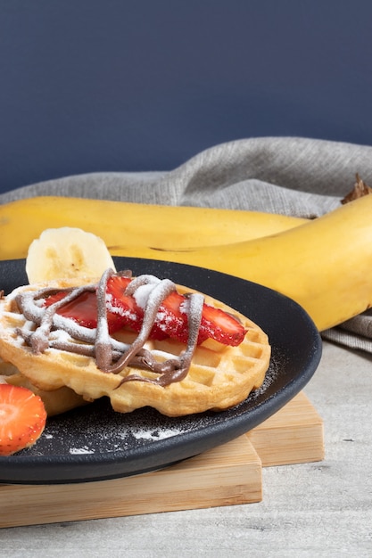 Waffle covered with strawberry, sugar and hazelnut.