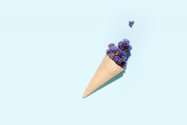 Waffle cup for ice cream with flowers on a blue space. copy space. summer concept