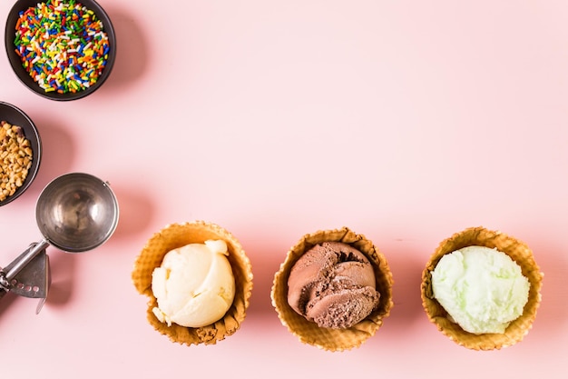 Waffle ice cream bowls with scoops of ice cream on a pink background.