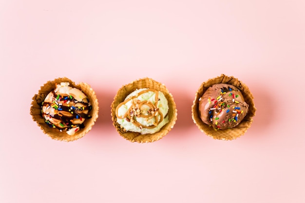 Waffle ice cream bowls with scoops of ice cream on a pink background.