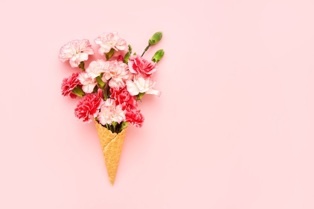 분홍색 벽에 빨간 카네이션 꽃과 와플 아이스크림 콘. 여름 개념. 공간 복사, 상단