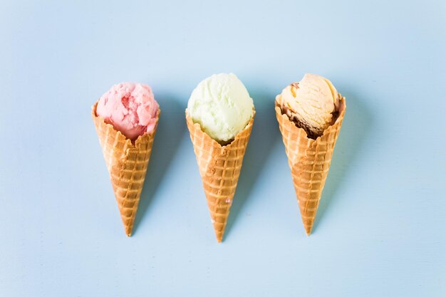 Waffle ice cream cones with scoops of ice cream on a blue background.