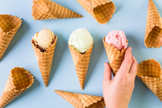 Waffle ice cream cones with scoops of ice cream on a blue background.