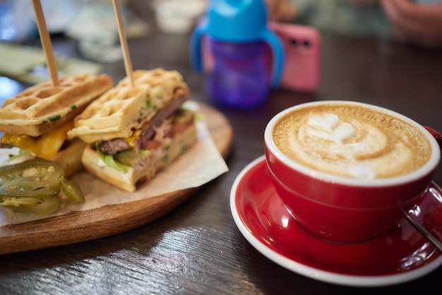 Waffle sandwich with meat cheese sauce and vegetables on wooden table background