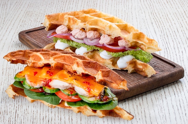 Waffle sandwich with salmon cream and turkey On a light wooden background