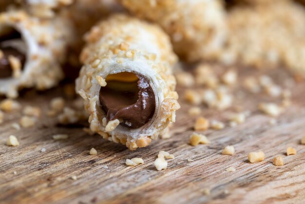 Waffle tube with chocolate filling and crushed peanuts