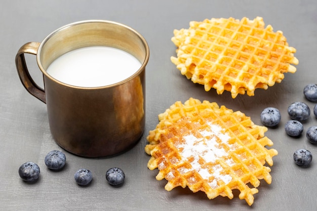 Waffles and berries on the table Milk in a metal mug