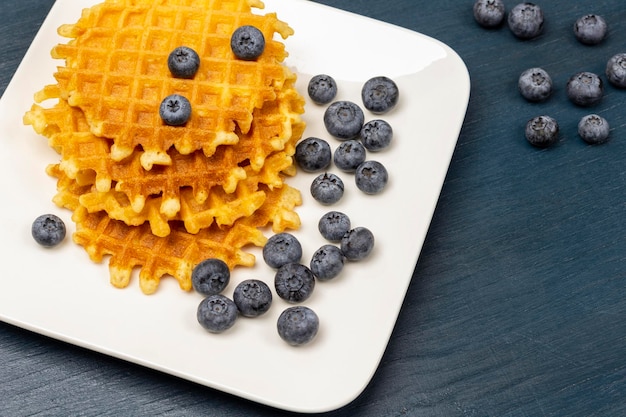 Waffles and blueberries on white plate Berries on table