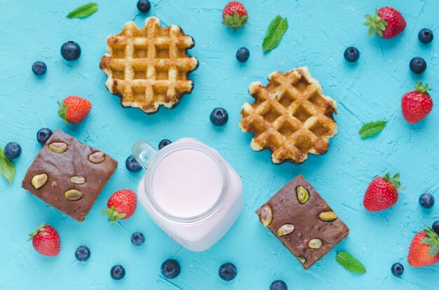 Waffles, brownies and berries on a blue table