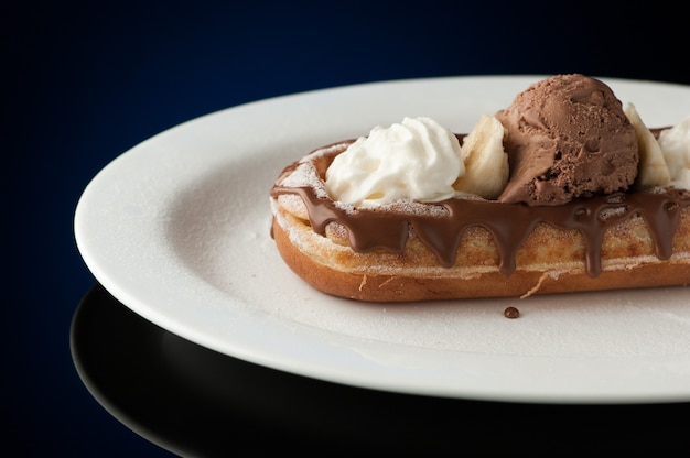 Waffles and ice cream in a dish on a dark background