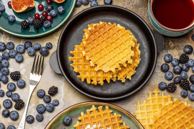 Waffles in a pan and on a plate Cup of tea and berries
