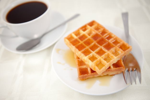 Waffles placed near a coffee cup