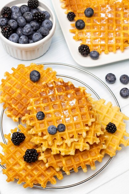 waffles on the table and on the plate blueberries and blackberries in a bowl