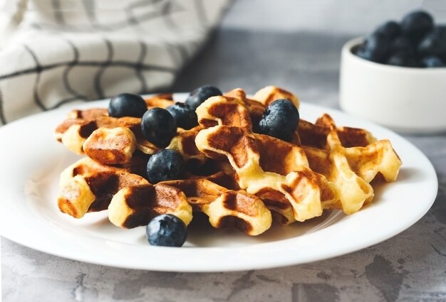 Waffles with blueberries on grey background