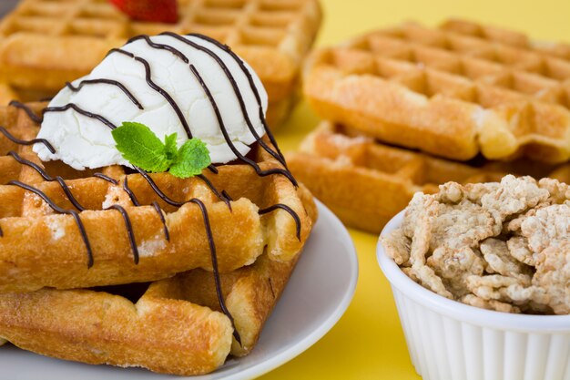 Waffles with chocolate sauce, ice cream and mint on yellow