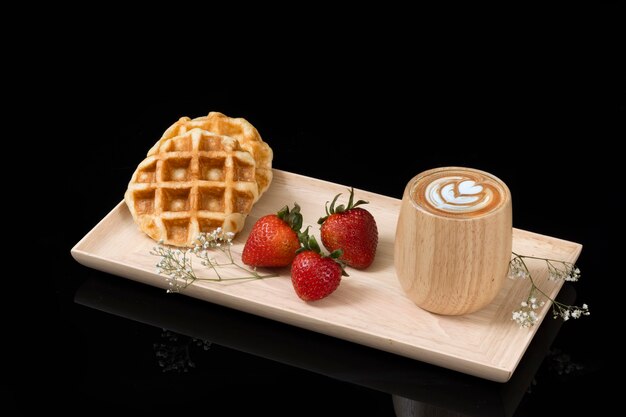 Waffles with fresh strawberries and a cup of cappuccino coffee.