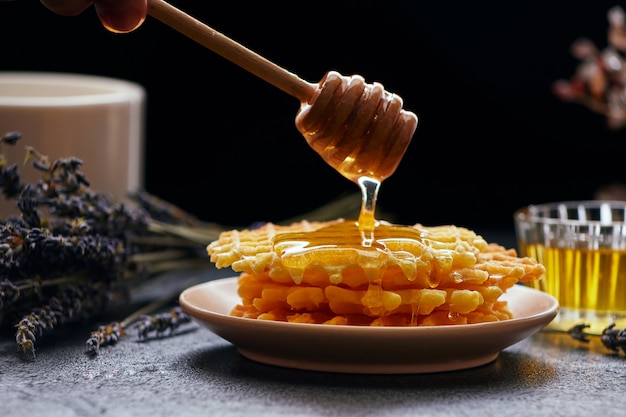 Waffles with honey on a dark background, close-up