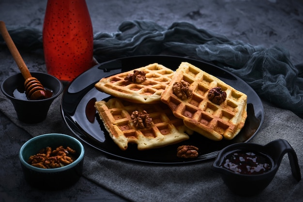 Waffles with honey on a dark surface, close-up