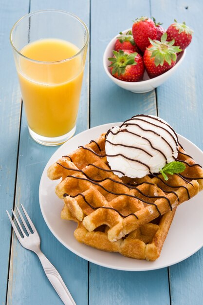 Waffles with ice cream on blue wooden table