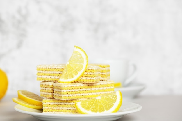 Photo waffles with lemon and milk filling. lemon slices lying on saucer on blurred background. yummy and sweet dessert. bun-fight. copy space. tea time concept.