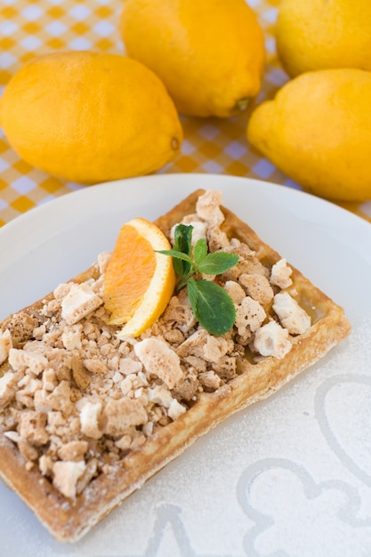 Waffles with meringue, lemon curls and orange slices for breakfast