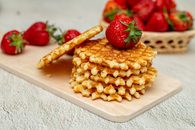 Waffles with strawberries on a white cutting board on a gray table