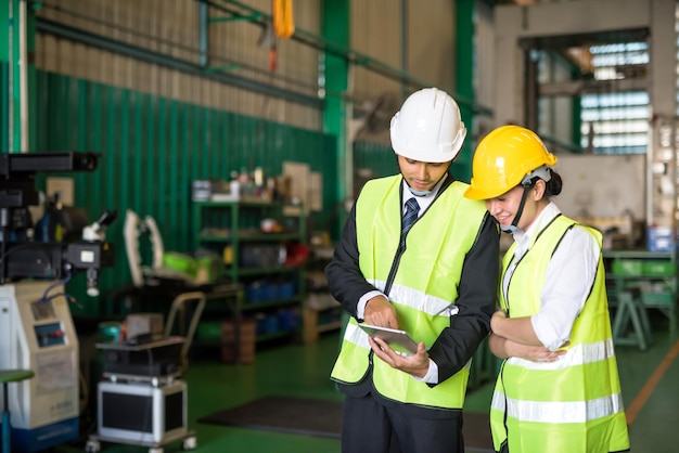 Waist up glimlachende Aziatische fabriek vrouwelijke werknemer en manager bespreken projectplan