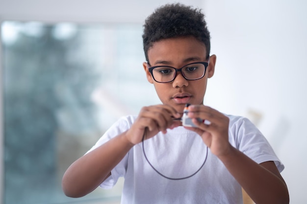 A waist up picture of a boy with a usb cable in hands