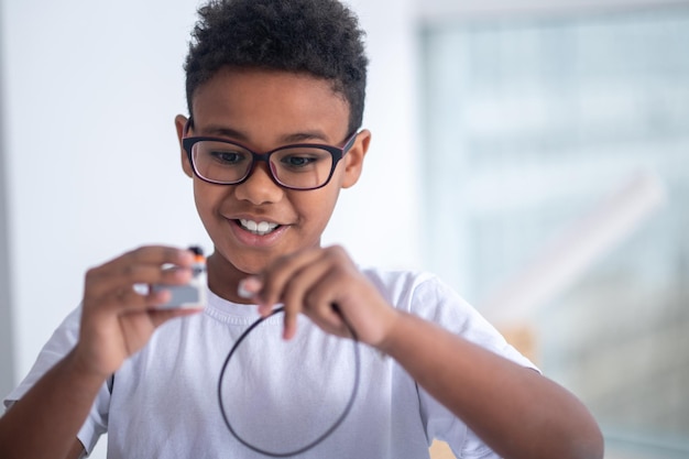 A waist up picture of a boy with a usb cable in hands