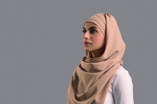 Photo waist up picture of a woman in hijab looking aside