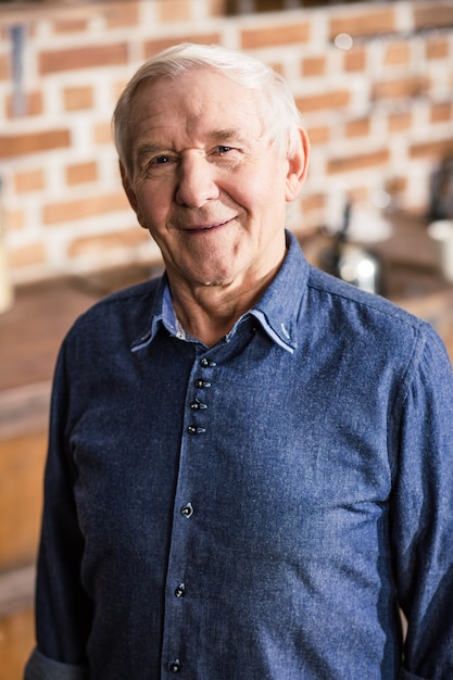 Photo waist up of pleasant positive man standing in the kitchen while smiling