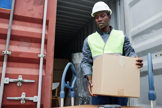 Waist up portrait of african american man unloading boxes from container at shipping docks copy spac