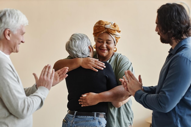 Photo waist up portrait of diverse group of elderly people applauding and embracing while celebrating succ