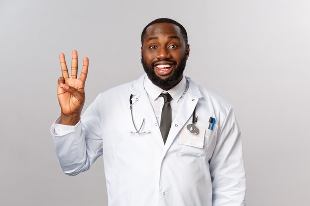 Waist-up portrait of handsome happy african-american male doctor, physician in white coat