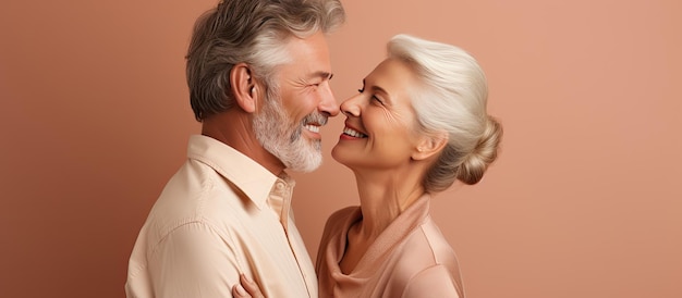 Waist up portrait of happy elderly couple embracing and gazing at each other on beige backdrop