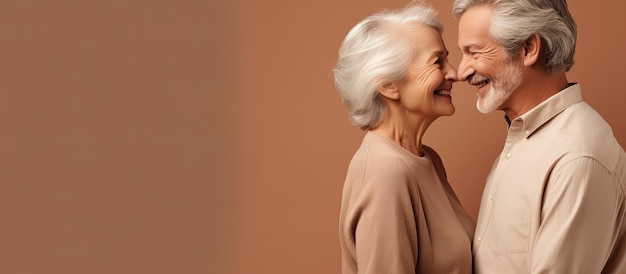 Waist up portrait of happy elderly couple embracing and gazing at each other on beige backdrop