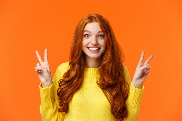 Waist-up portrait lovely and cheerful pretty redhead woman showing peace gestures