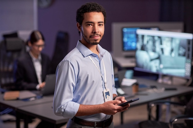 Waist up portrait of man looking at camera standing in office