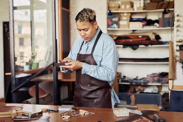 Waist up portrait of modern artisan working with leather in shop copy space