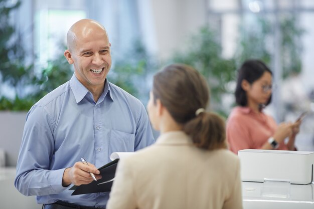 Фото Талия вверх портрет лысого зрелого бизнесмена, счастливо улыбающегося во время разговора с коллегой-женщиной