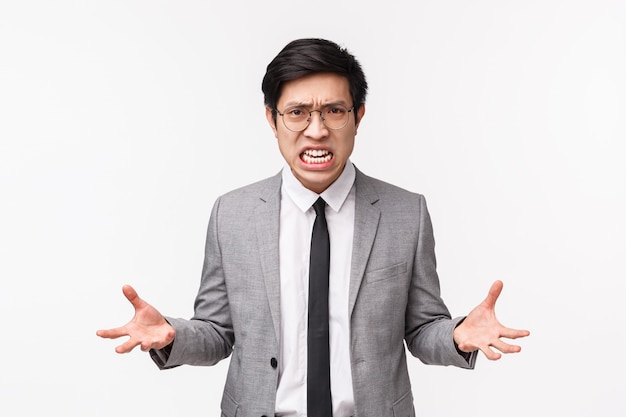 Waist-up portrait of outraged pissed-off young asian male office worker feeling aggressive and tensed, losing patience clench fists from hate and rage, grimacing bothered, boiling from anger