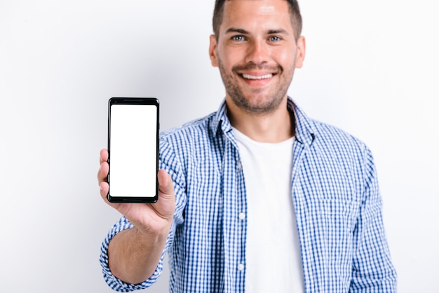 Waist up portrait of smiling bearded man holding smartphone with the screen to the camera and having wide smile. Technologies and people concept
