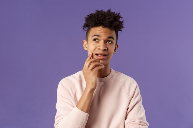 Waist-up portrait of thoughtful unsure young male student trying solve exercise