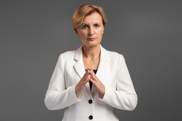 Waist up portrait view of the calm senior businesswoman holding arms folded and looking at the camera with serious expression