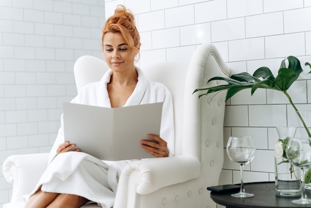 Waist up portrait view of the caucasian woman reading clients agreement while sitting at the armchair at the cosmetology clinic