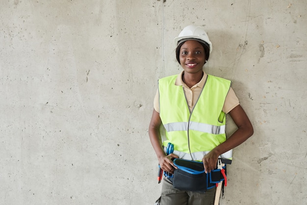 Photo waist up portrait of young africanamerican woman working at construction site and looking at camera ...