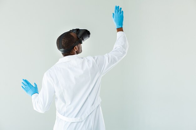 Waist up of professional doc using vr glasses against while wall