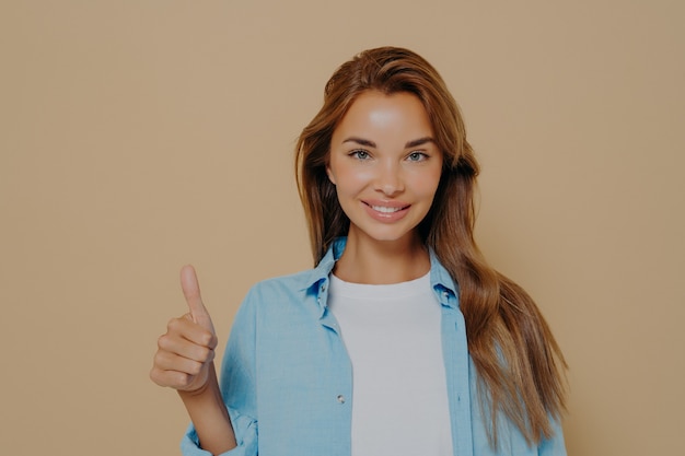 Waist up shot of satisfied supportive woman shows thumb up