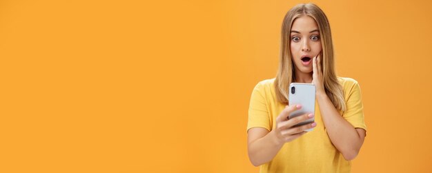 Waist-up shot of shocked and stunned emotive young woman reacting to shocking terrible news reading person